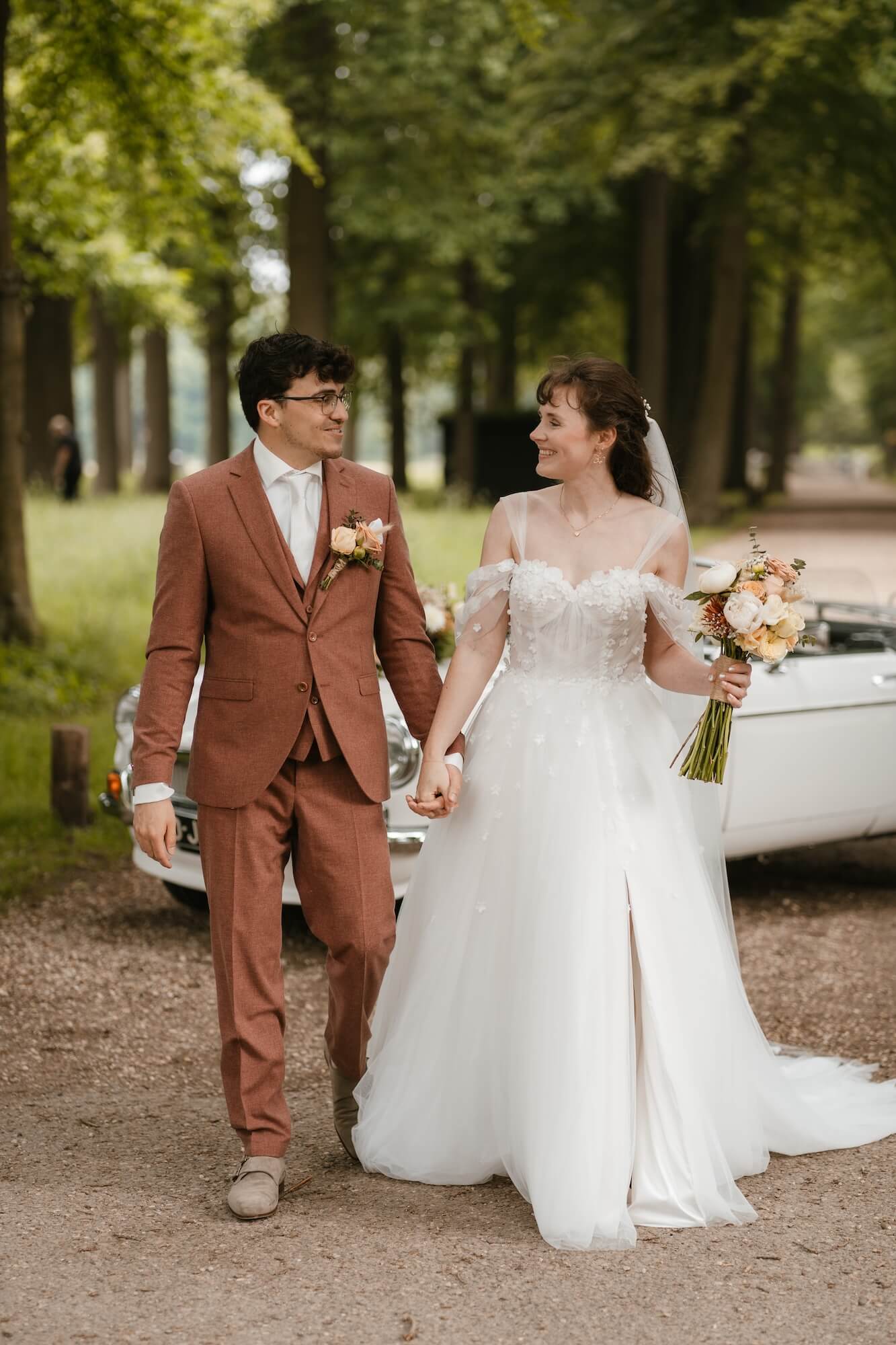 Bruidspaar voor witte vintage auto tijdens bruiloft in Barneveld, Gelderland